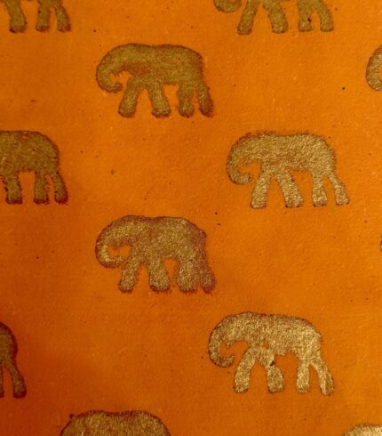 Zoom in ein handgemachtes, safranfarbenes Papiers mit goldenem Motiv eines Elefanten