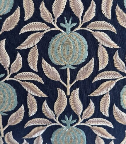 Zoom auf den dunkelblauen Kissenbezug aus Baumwolle mit Applikationen von Granatäpfeln in türkis mit silbrigen Blättern