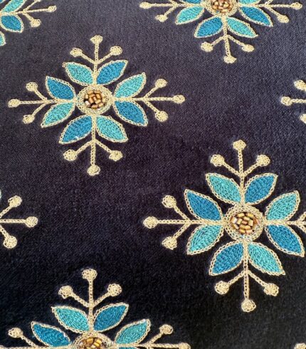 Zoom auf ein dunkelblaues Muster mit Applikationen von türkis, goldenen Schneeblumen