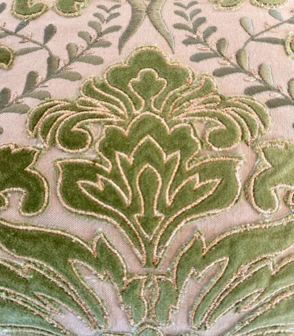 Zoom in einen cremefarbenen Baumwollkissenbezug mit grünen Lorbeerapplikationen