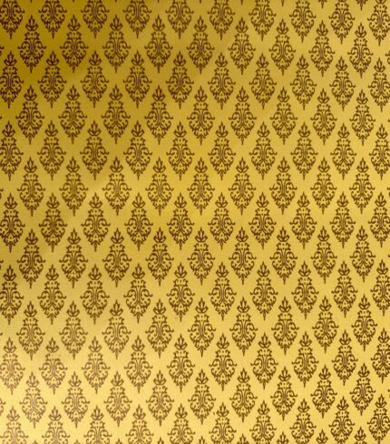 Frontalansicht eines handbedruckten, gelben Papiers mit braunen leicht schimmernden Ornamenten