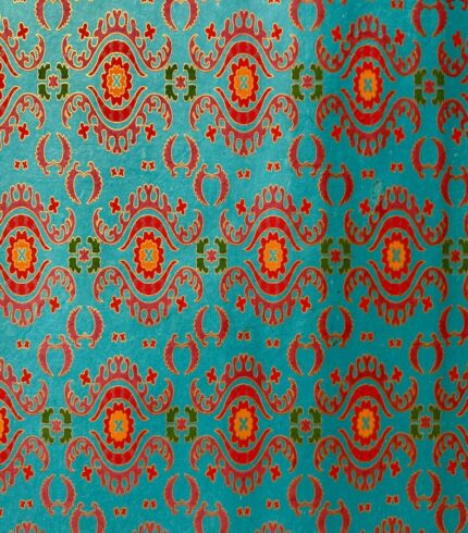 Frontalansicht eines handbedruckten, blautürkisen Papiers mit kräftigen rotorangenen Ornamenten unterbrochen von olivgrünen und pinken Ornamenten