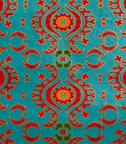 Zoom in ein handbedrucktes, Blautürkises Papier mit kräftigen rotorangenen Ornamenten unterbrochen von olivgrünen und pinken Ornamenten