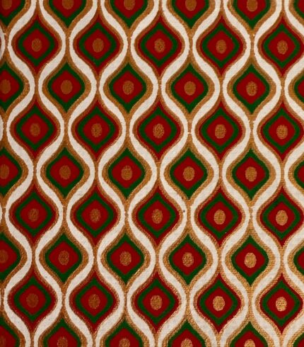 Zoom in ein handgefertigtes Notizbuch mit grün-rotem, tropfenförmigen Design in Gold umrandet.