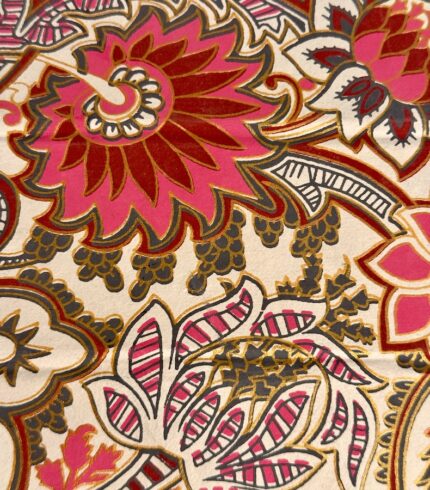 Zoom in einen handbedruckten, cremefarbenen Papierständer mit kräftigen rosafarbenen Blütenornamenten