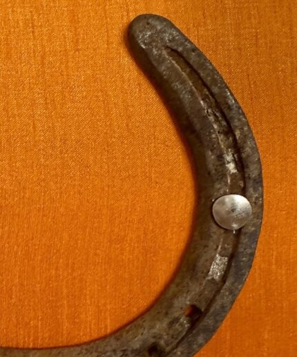 Zoom in ein Kunstwerk auf orangener Seide mit einem antiken Hufeisen mittig platziert