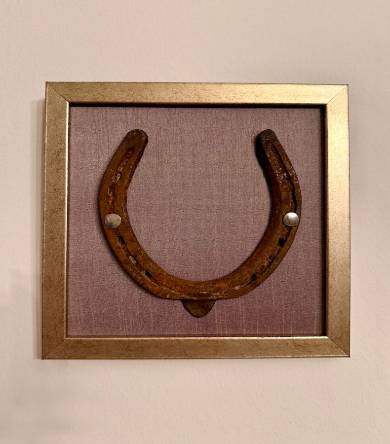 W011_1_v2 Frontalansicht eines Kunstwerk auf lavendelfarbener Seide mit einem antiken Hufeisen mittig platziert