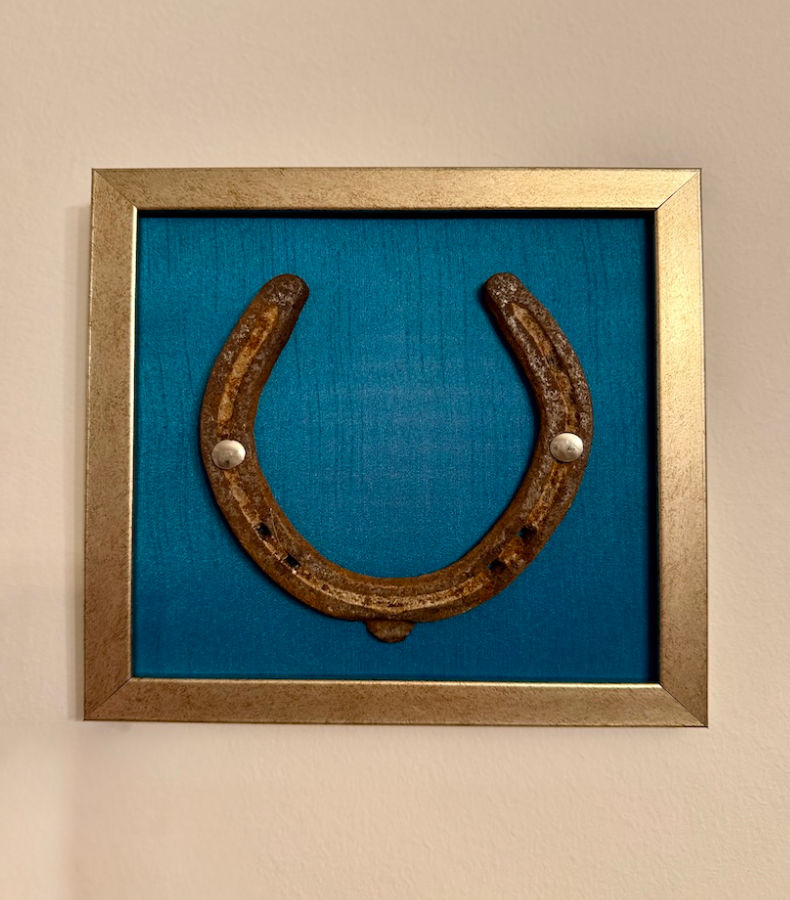 W015_1_v2 Frontalansicht eines Kunstwerk auf himmelblauer Seide mit einem antiken Hufeisen mittig platziert